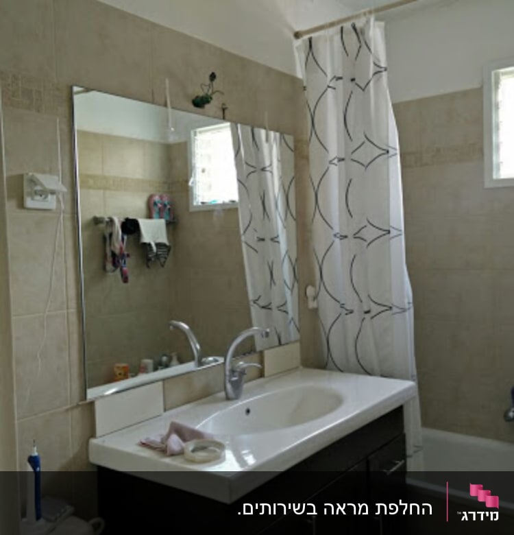 מראה גדולה מעל כיור בחדר אמבטיה
